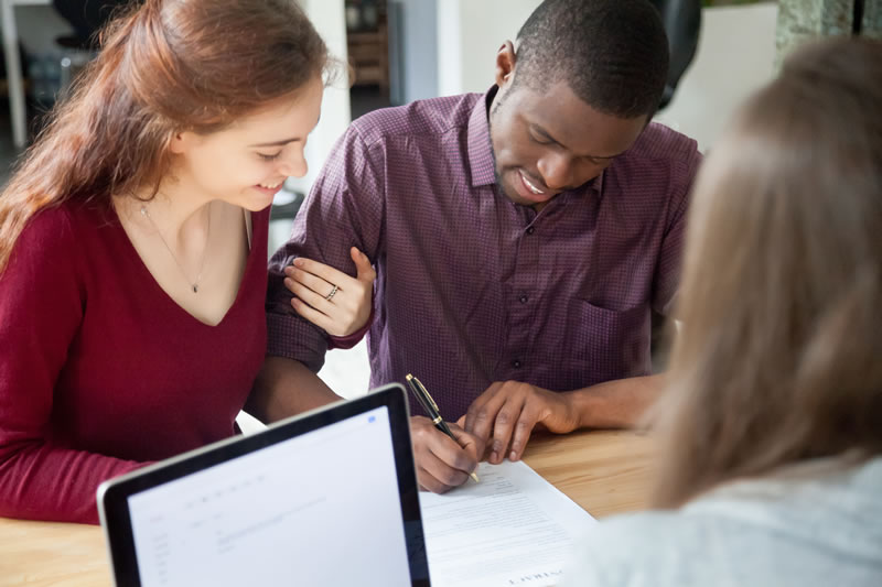 young couple signing documents at a table