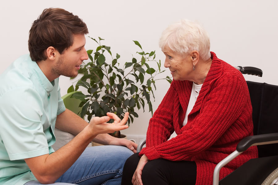 man talking to senior woman in wheelchair